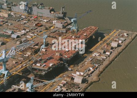 Steuerbord-Viertelansicht des nuklearbetriebenen Flugzeugträgers HARRY S. TRUMAN der Nimitz-Klasse, der im Trockendock 12 bei Newport News Shipbuilding und Drydock Corporation gebaut wird. Im linken Hintergrund befindet sich das MSC-Kfz-Transportschiff USNS GORDON (T-AKR-296), das am Liegeplatz 2 umgebaut wird. Basis: James River Bundesstaat: Virginia (VA) Land: Vereinigte Staaten von Amerika (USA) Stockfoto