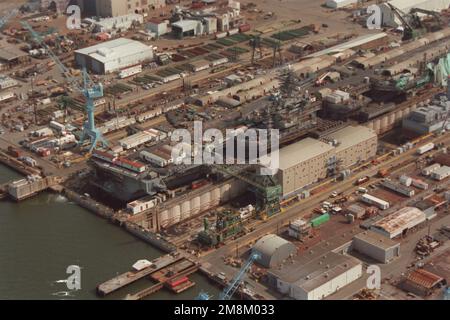 Viertelansicht des nuklearbetriebenen Flugzeugträgers US DWIGHT D. EISENHOWER (CVN-69) aus der Steuerbord-Luft im Trockendock 11 beim Newport News Shipbuilding and Drydock Corporation. Das Schiff wird einer umfassenden Überholung unterzogen. Ein Barackenschiff befindet sich links in Trockendock 10, um die Besatzung der Transportschiffe während der Instandsetzung des Schiffes zu versorgen. Basis: James River Bundesstaat: Virginia (VA) Land: Vereinigte Staaten von Amerika (USA) Stockfoto