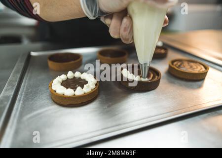 bäckercreme auf Schokoladenkuchen in der Bäckerei, Dessertkonzept. Hochwertiges Foto Stockfoto