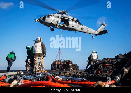 Ionisches Meer. 8. Januar 2023. Ein MH-60s Nighthawk Helikopter, der am Helicopter Sea Combat Squadron (HSC) 5 befestigt ist, liefert Lieferungen an das Cockpit des Flugzeugträgers USS George H.W. der Nimitz-Klasse Bush während einer Wiederauffüllung auf See mit dem schnellen Kampfschiff USNS Arctic der Versorgungsklasse (T-AOE 8), 8. Januar 2023. Kredit: USA Navy/ZUMA Press Wire Service/ZUMAPRESS.com/Alamy Live News Stockfoto