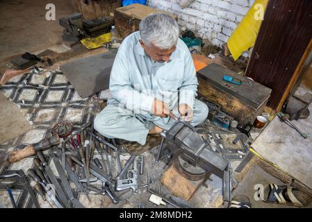 Ein Waffenschmied, der Revolver in der Waffenfabrik Peshawar, Pakistan, herstellt Stockfoto