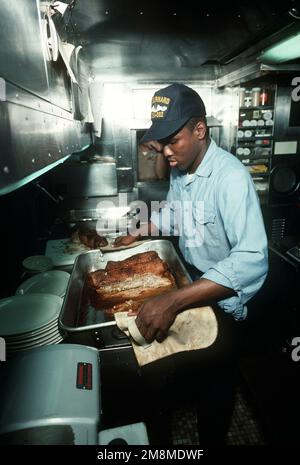 An Bord des nuklearbetriebenen Angriffs-U-Boots USS Gurnard (SSN-662) wird behauptet, dass U-Boote die besten der Welt essen, wenn sie über lange Zeiträume unter Wasser sind. Hier ist ein Gastronomiebetrieb auf gerollten Rumpsteak vorbereitet, was darauf hinweist, dass er auch im Hafen gut isst. Basis: San Diego Hafenstaat: Kalifornien (CA) Land: Vereinigte Staaten von Amerika (USA) Stockfoto