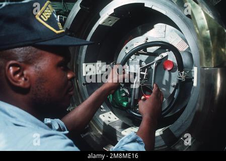 Ein Torpedoman an Bord des nuklearbetriebenen Angriffs-U-Boots USS Oklahoma City (SSN-723) führt nach dem Laden der Abschussrohre eine letzte Überprüfung durch. Land: Atlantik (AOC) Stockfoto