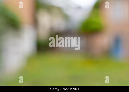 Hinterhof-Hintergrundbild. Abstraktes, verschwommenes Bild mit Gebäuden und grünem Gras. Der Raum ist leer und kann für die Konstruktion verwendet werden. Stockfoto