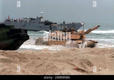 970628-M-9368G-015. [Complete] Szene Caption: Ein M1A1 Abrams Main Battle Tank (MBT) aus DEM 1. Panzerbataillon, 1. Marine Division, taucht während eines amphibischen Angriffs auf Red Beach während des Trainings KERNEL BLITZ '97 aus der Brandung auf. Der M1A1 Abrams wurde auf einem Landing Craft, Utility (LCU) transportiert, wie es im Hintergrund zu sehen ist. KERNEL BLITZ ist eine zweijährliche Flottenübungsübung (FLEETEX) des Oberbefehlshabers der Pazifikflotte (CINCPAC) mit Schwerpunkt auf operativer/taktischer Ausbildung des Befehlshabers der Third Fleet (C3F)/ I Marine Expeditionary Forces (MEF) und des Befehlshabers der Amphibien Gruppe 3 (CPG-3)/ 1. Marine Division ( Stockfoto