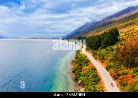 Rotes Auto auf dem Highway 6 entlang des Lake Wkatipu in Otago von Neuseeland - malerische Luftlandschaft. Stockfoto