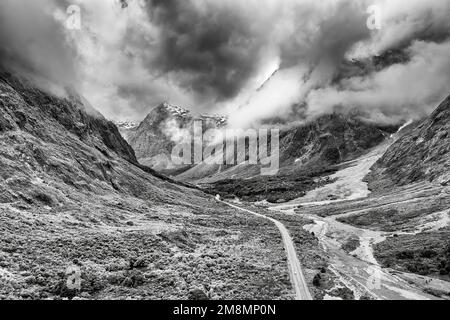 Dramatischer Schwarzweiß-Blick auf den One Key Creek Valley Highway zum Milford Sound Fjord in Neuseeland - malerische Berglandschaft. Stockfoto