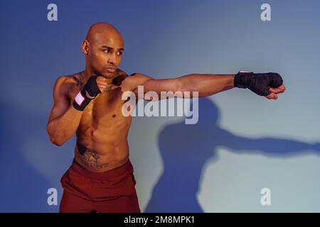 Professioneller Kickboxer ist Training und Punch im Studiohintergrund mit Schatten Stockfoto