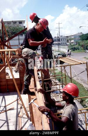 SENIOR AIRMAN Seth Mellott, 820. Rapid Engineer Deployable Heavy Operations Repair Squadron Engineering Squadron, Nellis Air Force Base, NV, weist den Lance Corporal Ebbionne Stevens der Guyana Defense Force an, wo die Dachverbindung am Rahmen des Gebäudes befestigt werden soll. Militärangehörige von Red Horse, USA Die Marine Corp und die Guyana Defense Force, die der Combined Task Force Falcon zugeteilt wurden, schlossen sich zusammen, um die St. Mary's High School im Rahmen der ersten kombinierten humanitären und zivilen Hilfsaktion zwischen den Vereinigten Staaten und Guyana wieder aufzubauen. Militärpersonal der Air Force, Ai Stockfoto