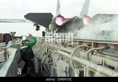 US Navy Aviation Boatswain Mate (Betreiber von Launch- und Bergungsgeräten) 3. Klasse (AB3) Joshua Schwandt signalisiert einen klaren Start eines F-14 Tomcat aus dem Katapult auf der Hafenseite des Schiffes. An Bord des konventionellen Flugzeugträgers USS INDEPENDENCE (CV 62), der im Persischen Golf eingesetzt wird, um während der Operation SOUTHERN WATCH am 22. Februar 1998 UN-Sanktionen gegen Irak durchzusetzen. Betreff Betrieb/Serie: SÜDLICHE WACHSTATION: USS Independence (CV 62) Stockfoto
