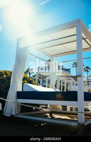 Beach Lounge Urlaub und Sommerblick auf einige Betten in einem Beach Club an einem weißen Sandstrand auf Teneriffa. Strandliegen zwischen Palmen im perfekten tropischen Stil Stockfoto