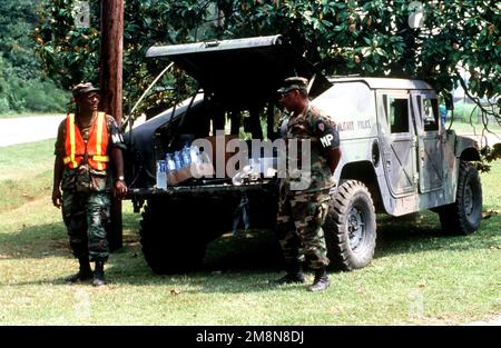 Zwei Mitglieder des Militärpolizeigeschwaders der North Carolina Army National Guard stehen bereit, um nach Hurrikan Bonnie Plastikflaschen Wasser aus dem Kofferraum ihres M1114 Heavy High-Mobility Multipurpose Wheeled Vehicle (HMMWV) herauszugeben. Basis: Kinston Bundesstaat: North Carolina (NC) Land: Vereinigte Staaten von Amerika (USA) Stockfoto