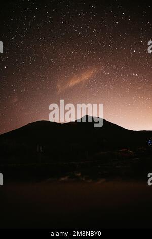 Berge bei Nacht und Sterne am Himmel, der große Bär, fallende Sterne und Planeten am Himmel. Verrauschtes Foto bei langer Belichtung Stockfoto