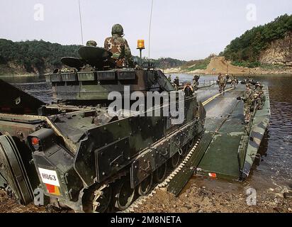 Ein m2 Bradley-Kampffahrzeug, das der 2-9. Infanterie, Camp Casey, Republik Korea (ROK), zugewiesen wurde, besteigt eine teilweise montierte Pontonbrücke, die von den 50. Engineers, 1. Platoon, Camp LaGuardia, ROK, gebaut wurde, während sie den Imjin River, ROK überqueren, während einer Brückenbauübung am 22. Oktober 1998. Viele der Teilnehmer an der heutigen Übung sind Offiziere, die gemäß dem US Army Officer Professional Development Program teilnehmen, einem Programm zur Verbesserung der Teambildung und der Soldatenbildung. Betreff Betrieb/Serie: KOREA CD Base: Imjin River Country: Republik Korea (KOR) Stockfoto