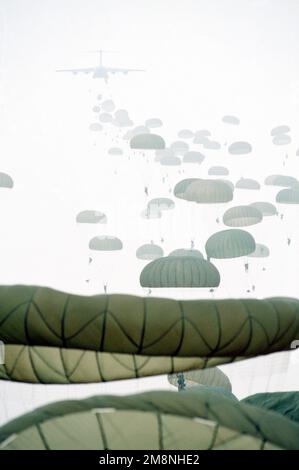 Rückansicht des USAF C-17 Globemaster III, während die US Army Airborne Truppen von hinten fallen. Fallschirmspringer-Fallschirmschirme sind im Vordergrund bis zum Hintergrund zu sehen. Dieses Bild stammt aus der Januar 1999 Ausgabe des AIRMAN Magazine, in der die Expeditionary Aerospace Force vorgestellt wird. Land: Unbekannt Stockfoto