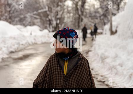 Srinagar, Indien. 15. Januar 2023. Ein Junge sieht zu, wie er nach starkem Schneefall am Stadtrand von Srinagar auf einer Straße läuft. Aufgrund des starken Schneefalls gab es mehrere Lawinen an verschiedenen Orten Kaschmirs. Der Zeitraum von 40 Tagen von Dezember 21 bis Januar 31., auch bekannt als Chilai Kalan, in Kaschmir gilt als der wichtigste Zeitraum, wenn es schneit, wird der Zustand noch schlimmer. Kredit: SOPA Images Limited/Alamy Live News Stockfoto