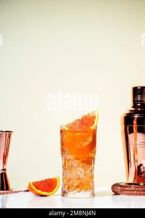 Grand Sazerac Cocktail mit Whiskey, Likör, Bitter, Absinth, Prosecco, Garniert mit Orangenschale in Highball-Glas. Beiger Hintergrund, hartes Licht, Stockfoto