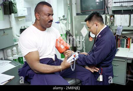 US Navy Store Keeper erste Klasse Leo Suber hat seine Vitalzeichen in der medizinischen Praxis an Bord der USS NICHOLAS (FFG 47) von US Navy Hospital Corpsman dritte Klasse Stephen Albright aufgenommen. Nicholas ist vorwärts in die Adria einmarschiert. Basis: USS Nicholas (FFG 47) Land: Auf See Stockfoto