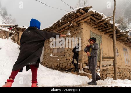 Srinagar, Indien. 15. Januar 2023. Kinder spielen mit Schnee vor ihrem Schlammhaus nach einem schweren Schneefall in den Außenbezirken von Srinagar. Aufgrund des starken Schneefalls gab es mehrere Lawinen an verschiedenen Orten Kaschmirs. Der Zeitraum von 40 Tagen von Dezember 21 bis Januar 31., auch bekannt als Chilai Kalan, in Kaschmir gilt als der wichtigste Zeitraum, wenn es schneit, wird der Zustand noch schlimmer. (Foto: Idrees Abbas/SOPA Images/Sipa USA) Guthaben: SIPA USA/Alamy Live News Stockfoto