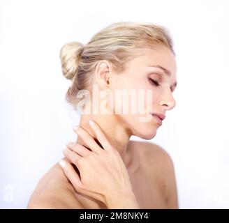 Seidig weich. Eine junge Frau streichelte ihren Hals, während sie auf Weiß isoliert war. Stockfoto