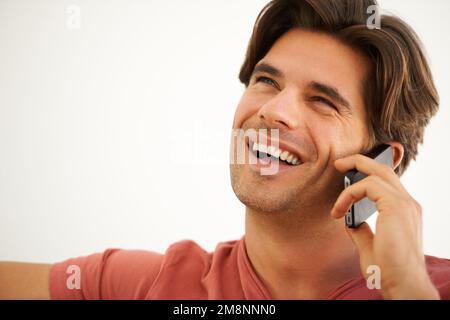 Ich genieße ein ungezwungenes Gespräch. Ein gutaussehender junger Mann, der mit jemandem auf seinem Handy spricht. Stockfoto