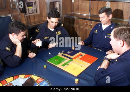 Chilenische Offiziere an Bord der USS TUCSON (SSN 770), spielen ein Spiel "Uckers" mit US Navy Commander Dennis Murphy, Commanding Officer (3. von links) und US Navy Lieutenant Commander James Pitts, Executive Officer (rechts) nach dem Abendessen in der Offiziersmesse, während er an der Übung DER TEAMARBEIT SOUTH '99 vor der Küste Chiles teilnahm. Reuben James wird bilaterale Operationen mit der chilenischen Marine durchführen. Betreff Betrieb/Serie: TEAMWORK SÜD '99 Basis: USS Tucson (SSN 770) Stockfoto