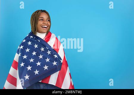 Afrikanische Frau, die zur Seite schaut, in einer nordamerikanischen Flagge verpackt Stockfoto