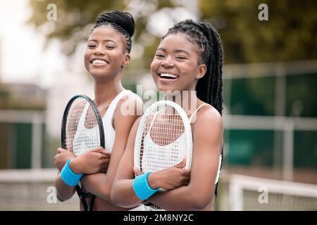 Porträt von fröhlichen Tennisspielern, die Schläger halten. Junge Freunde, bereit fürs Tennistraining auf dem Platz. afroamerikanische Tennisspieler lachen Stockfoto