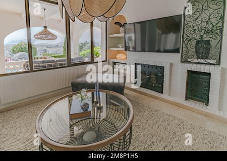 Kleiner Couchtisch vor einem an der Wand montierten Fernseher und Kamin Stockfoto