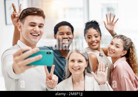 Eine Gruppe fröhlicher und vielseitiger Geschäftsleute, die gemeinsam ein Selfie bei der Arbeit machen. Glücklicher weißer Geschäftsmann, der ein Foto mit seinen Kollegen macht Stockfoto