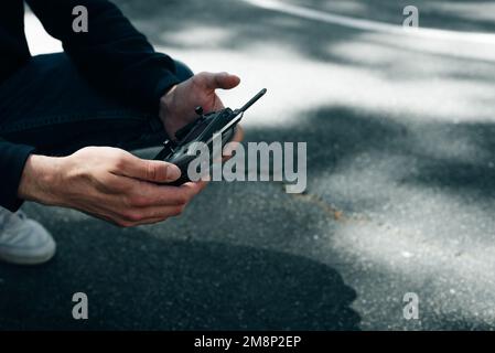 Der Mann hält die Fernsteuerung mit den Händen und steuert die Drohne. Hochwertiges Foto Stockfoto