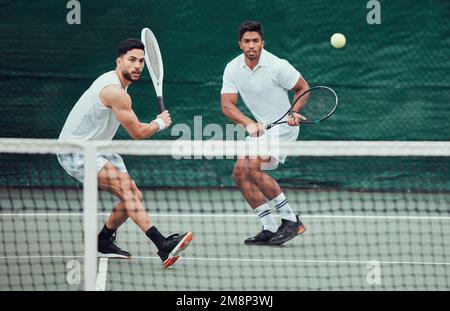 Zwei ethnische Tennisspieler, die Schläger halten und auf einem Platz spielen. Ein ernsthaftes, fokussiertes Team von Athleten, die während des Spiels zusammen sind. Wettkampf spielen Stockfoto