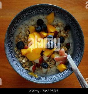 Tropischer Frühstücksbrei mit Mango und Blaubeeren Stockfoto