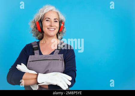 Reife Zimmermannsarbeiterin mit Werkzeug und Arbeitskleidung Stockfoto