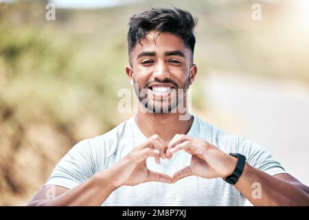 Portrait Happy Fit junger Mann aus gemischten Rassen, der beim Training im Freien mit den Händen ein Herz geformt. Ein gutaussehender lateinamerikanischer Mann, der zeigt, dass er es liebt Stockfoto