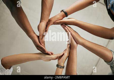 Nahaufnahme einer Gruppe von Kollegen, die ihre Hände zusammenlegen, um im Büro von unten einen Kreis zu bilden. Kreatives Team, das sich an den Händen hält und Einigkeit zeigt Stockfoto