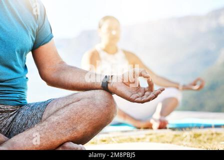 Nahaufnahme eines älteren Mannes und einer älteren Frau, die in Lotusposition sitzen und während des Yoga-Trainings in der Natur Meditation praktizieren und sich ruhig fühlen. Rentner Stockfoto