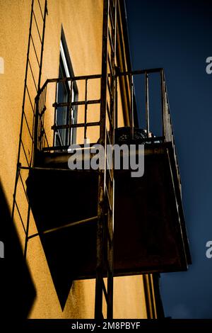 Ein kleiner Winkel von einem alten rostigen Balkon eines gelben Gebäudes an einem sonnigen Tag Stockfoto