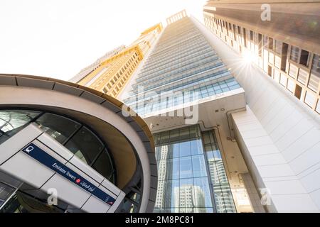 Perspektive der U-Bahn-Haltestelle Emirates Towers in Dubai mit nahe gelegenen Wolkenkratzern, die sich in einen sonnigen Himmel hineinragen Stockfoto