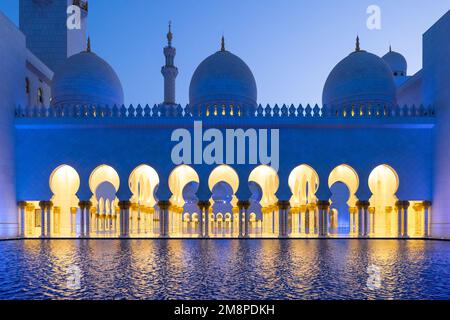 SideView während der blauen Stunde der majestätischen Scheich-Zayed-Moschee in Abu Dhabi, die sich auf dem Wasser spiegelt Stockfoto