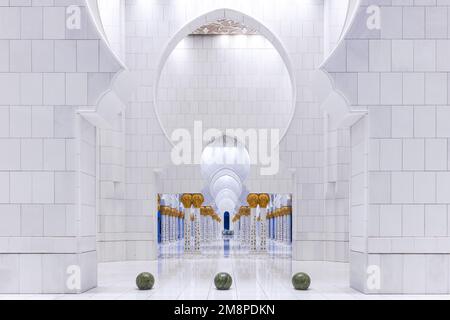 Symmetrischer Blick auf eine weiße Marmorkolonnade in der Scheich-Zayed-Moschee in Abu Dhabi Stockfoto