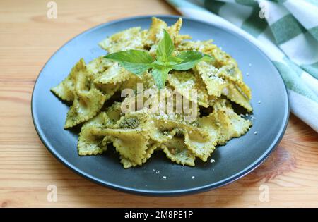 Ein Teller Farfalle oder Fliege Pasta in Pesto Sauce, serviert auf einem Holztisch Stockfoto