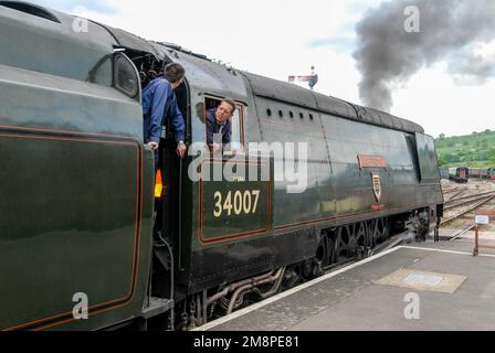 Fahrer und Feuerwehrmann auf der Fußplatte der 1945 gebauten 34007 Dampflok an der Winchcombe Station in den Cotswolds in Großbritannien. Es ist Teil des Erbes Stockfoto