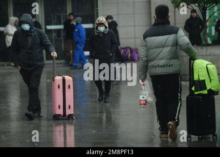 HANGZHOU, CHINA - 15. JANUAR 2023 - Passagiere trauen sich dem Schnee, um den Bahnhof von Hangzhou zu betreten und den Zug nach Hause zu nehmen, um den MondNeujahrsfeiertag zu feiern.i Stockfoto