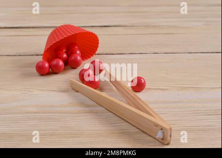 Pädagogische Spiele für Kinder. Bälle und Pinzetten für die Feinmotorik. Stockfoto