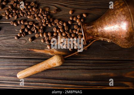 Türkische Kupferzeze und Kaffeebohnen auf Holzhintergrund. Das Konzept des frisch gebrühten Kaffees. Stockfoto