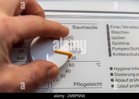 Hand auf den Temperaturregler einer Waschmaschine legen Stockfoto