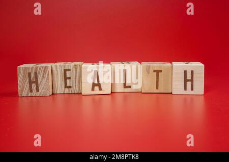 Chinesisches Neujahrskonzept. Gesundheitswort auf Holzblock auf rotem Hintergrund geschrieben. Isoliertes Rot. Stockfoto