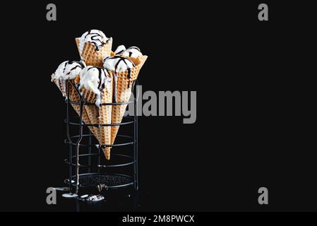 Hütchen aus hausgemachtem Vanilleeis mit Schokolade auf dunklem Hintergrund. Kopierbereich Stockfoto