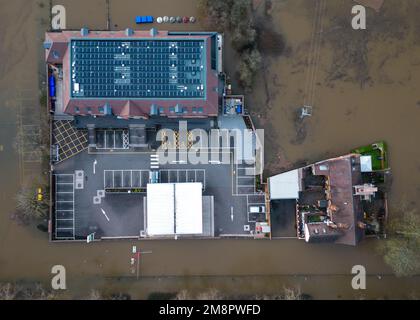 Upton Upon Severn, Worcestershire, 15. Januar 2023 – die Stadt Upton-upon-Severn ist fast abgeschnitten, mit nur einer Straße in und einer Straße, nachdem der Fluss Severn begonnen hatte, über erhöhte Flussufer zu fließen und die umliegenden Felder zu überschwemmen. Eine Tankstelle und ein lokaler Morrisons Supermarkt waren zu einer Insel aus der Flut geworden. Zwei Spaziergänger wurden auf einem Bauernfeld gesehen, wie sie ihren Weg durch flaches Wasser machten, während sie mit ihrem Hund gingen. Quelle: Stop Press Media/Alamy Live News Stockfoto